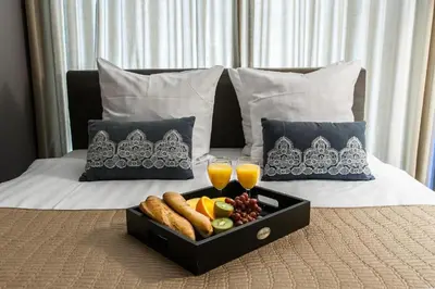 a tray of food on a bed with two glasses of orange juice at Hotel Mosaic Apartments in Amsterdam