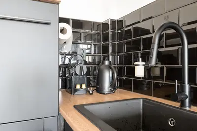 a kitchen counter with a sink and black tiles at Beach Villa & Studio in Zandvoort
