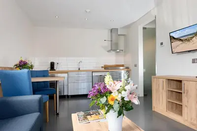 a kitchen and living room with a vase of flowers at Droomvakanties Egmond Appartement van Speijk in Egmond aan Zee