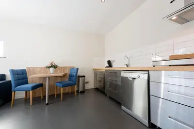 a kitchen with a table and blue chairs at Droomvakanties Egmond Appartement van Speijk in Egmond aan Zee