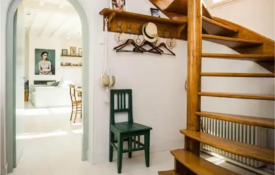 a room with a staircase and a green chair at Zeevilla Duinhorst in Bergen aan Zee