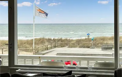 a view of the beach from a window with a flag at Zwaluwnest in Bergen aan Zee