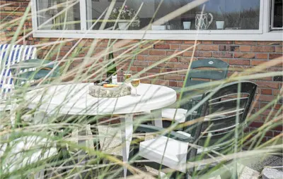 a white table with chairs and a glass of wine at Duinennest in Bergen aan Zee