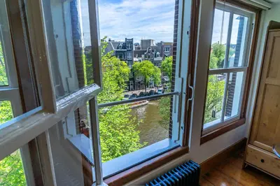 a room with windows with a view of a river at B&B Singel Suites in Amsterdam