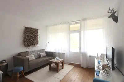 a living room with a couch and a window at Appartementen aan zee in Egmond aan Zee