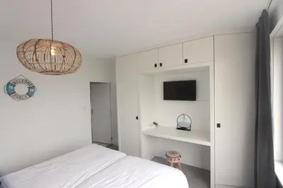 a white bedroom with a bed and a chandelier at Appartementen aan zee in Egmond aan Zee