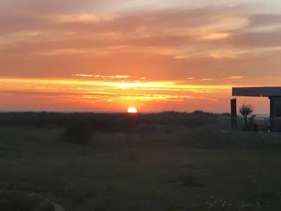a sunset over a field with the sun setting at Appartementen aan zee in Egmond aan Zee