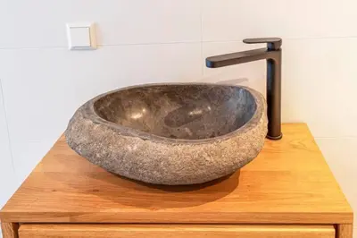 a large rock sink sitting on top of a wooden table at klaproos Bergen NH in Bergen