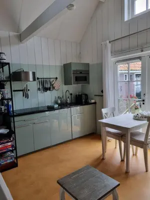 a kitchen with white cabinets and a table and a window at Bed en breakfast Onder aan de dijk in Warder