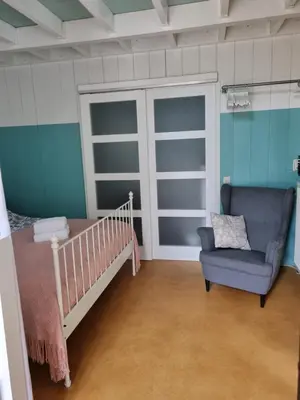 a bedroom with a crib and a chair in it at Bed en breakfast Onder aan de dijk in Warder
