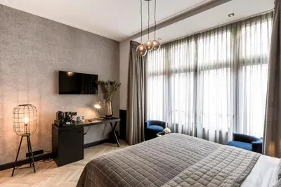 a bedroom with a bed and a desk and a television at Cavallaro Hotel in Haarlem