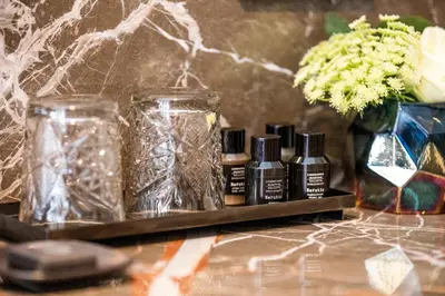 three bottles of essential oils and a vase with flowers at Cavallaro Hotel in Haarlem