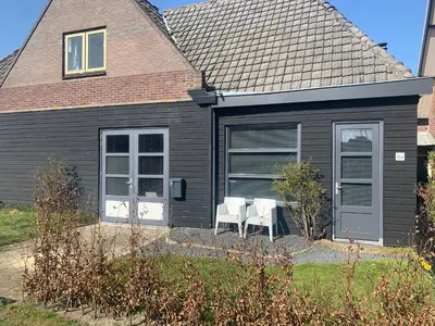 a black house with two white chairs in front of it at Smederij Schoorldam in Schoorl