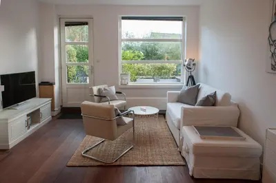 a living room with a couch and chairs and a tv at Smederij Schoorldam in Schoorl