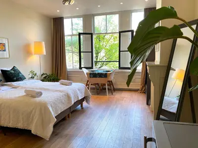 a bedroom with a bed and a table and windows at The Canalview Retreat in Amsterdam