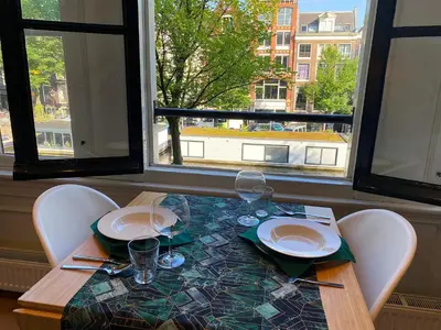 a table with chairs and plates and glasses and a window at The Canalview Retreat in Amsterdam
