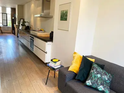 a living room with a couch and a kitchen at The Canalview Retreat in Amsterdam