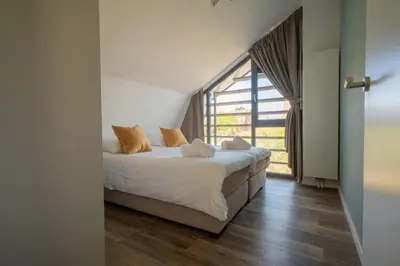 a bedroom with a bed and a large window at Zicht op de Molen by Droomvilla in Egmond aan den Hoef