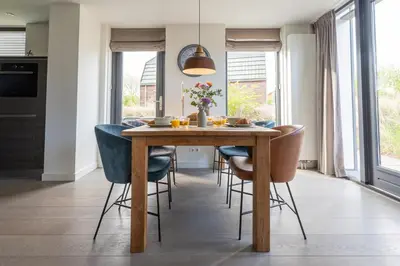 a dining room with a wooden table and blue chairs at Zicht op de Molen by Droomvilla in Egmond aan den Hoef