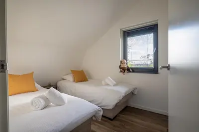 a room with two beds and a window at Zicht op de Molen by Droomvilla in Egmond aan den Hoef