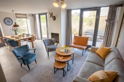 a living room with a couch and chairs and a table at Zicht op de Molen by Droomvilla in Egmond aan den Hoef