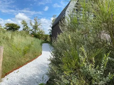 a small path leading to a building with bushes at Zicht op de Molen by Droomvilla in Egmond aan den Hoef