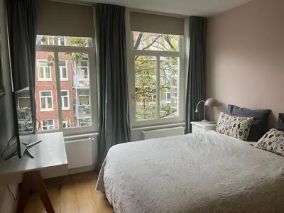 a bedroom with a bed and two large windows at Great Apartment Amsterdam in Amsterdam