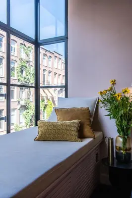 a bed with a pillow and a large window at Luxurious Residence in Vondelpark/Museum District in Amsterdam