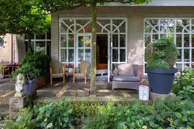 a screened in porch of a house with chairs and plants at Amsterdamgarden - stunning garden villa with pool close to Amsterdam in Laren