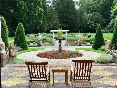 two chairs and a table in a garden with a fountain at Amsterdamgarden - stunning garden villa with pool close to Amsterdam in Laren