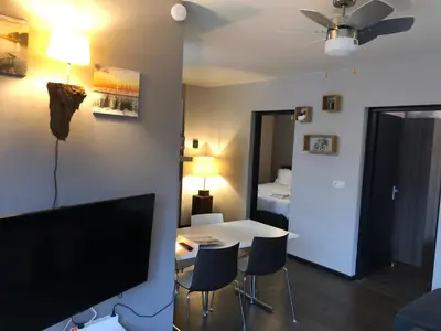 a living room with a television and a table and chairs at Casa The Wave with infrared sauna in Noordwijkerhout