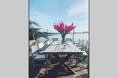 a wooden table with a vase of red flowers on it at Casa The Wave with infrared sauna in Noordwijkerhout