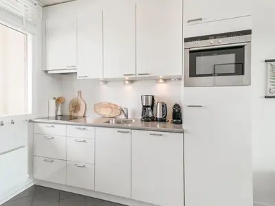 a white kitchen with white cabinets and a refrigerator at Apartment near North Sea and Lighthouse in Egmond aan Zee