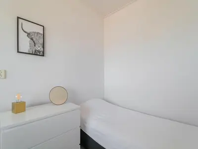 a white bedroom with a bed and a mirror at Apartment near North Sea and Lighthouse in Egmond aan Zee