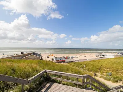 a view of the beach from the top of a boardwalk at Apartment near North Sea and Lighthouse in Egmond aan Zee