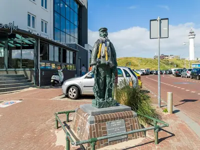 a statue of a man standing next to a street at Apartment near North Sea and Lighthouse in Egmond aan Zee