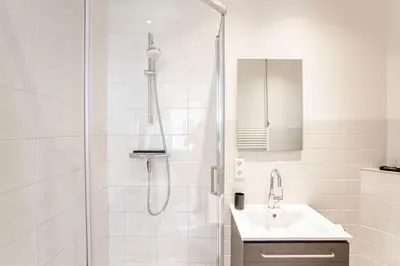 a white bathroom with a shower and a sink at Casa by Sellas in Zandvoort