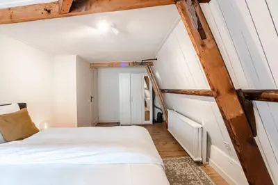 a small attic bedroom with a bed and a ladder at Casa by Sellas in Zandvoort
