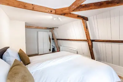 a bedroom with a white bed with wooden beams at Casa by Sellas in Zandvoort