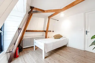 a room with a white bed in a attic at Casa by Sellas in Zandvoort