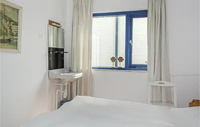 a bedroom with a bed and a sink and a window at Bergenhuisje in Bergen aan Zee