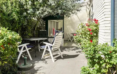 a patio with a table and chairs and flowers at Bergenhuisje in Bergen aan Zee