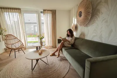 a woman sitting on a couch reading a book at Dromen in de duinen by Droomvilla in Sint Maarten