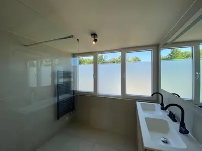 a bathroom with a sink and a shower and windows at Dromen in de duinen by Droomvilla in Sint Maarten