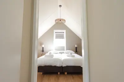 a bedroom with two beds and a window at Dromen in de duinen by Droomvilla in Sint Maarten