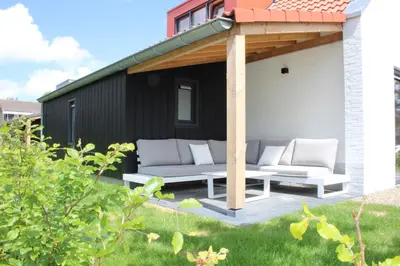 a patio with two white couches under a pergola at Dromen in de duinen by Droomvilla in Sint Maarten