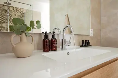 a bathroom sink with a vase with wine bottles on it at Slapen tussen de duinen by Droomvilla in Sint Maarten