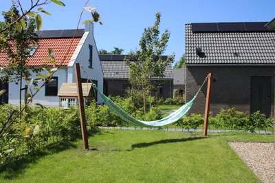 a hammock in the yard of a house at Slapen tussen de duinen by Droomvilla in Sint Maarten