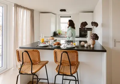 a kitchen with a black counter and three chairs at Ultiem genieten in Sint Maarten by Droomvilla in Sint Maarten