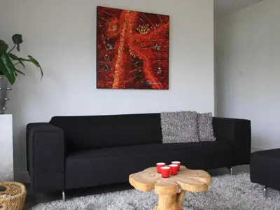 a living room with a black couch and a table at Riverside holiday home near Amsterdam in Nigtevecht
